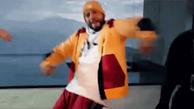 a man in a yellow and red jacket is dancing in a room .
