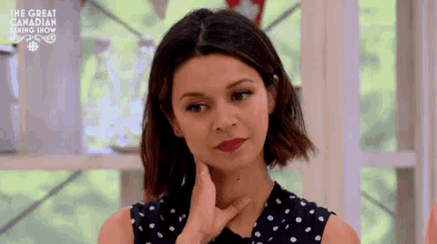 a woman in a polka dot dress is making a funny face with her hand on her chin .