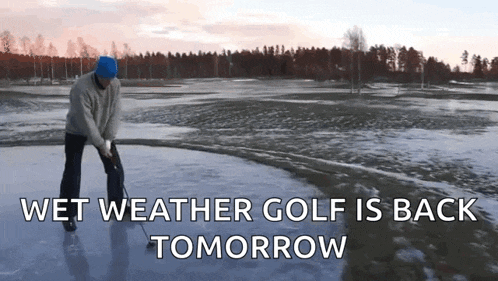 a man is swinging a golf club on a wet weather golf course