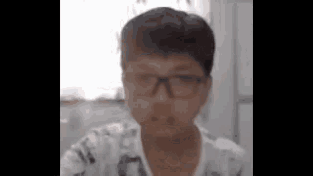 a young boy wearing glasses and a white shirt is sitting at a table .