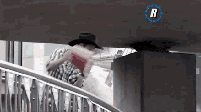 a man wearing a cowboy hat is standing on a staircase
