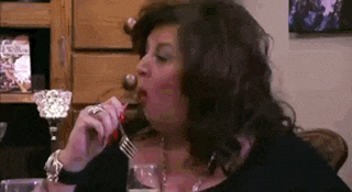 a woman is holding a fork in her mouth while eating .