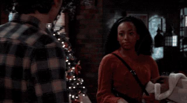 a man in a plaid shirt is standing next to a woman in a red sweater