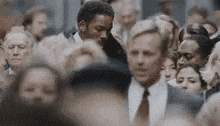 a man in a suit is standing in a crowd of people .