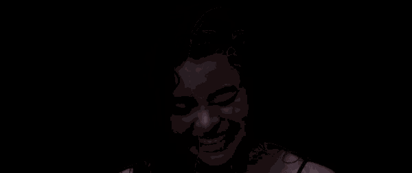 a woman is laughing in the dark with her mouth open .