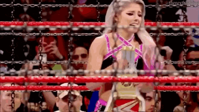 a female wrestler is holding a trophy in a ring