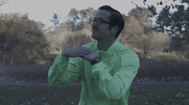 a man with glasses and a green jacket is stretching his arms