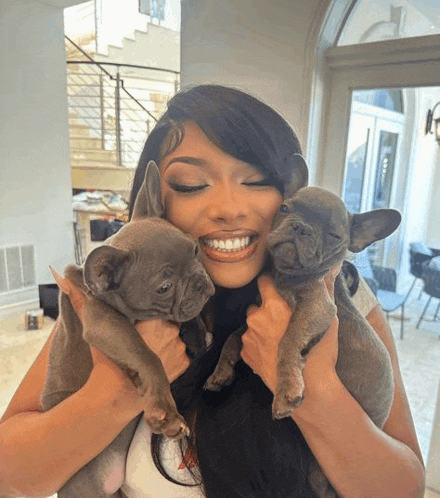 a woman is holding two puppies in her arms and smiling for the camera