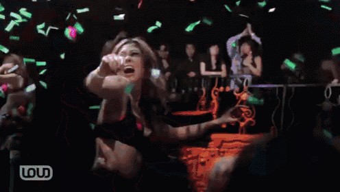 a woman in a bikini is dancing in front of a crowd with loud written on the bottom right