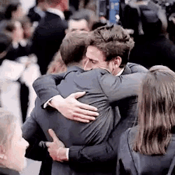 a man in a suit hugging another man in a crowd of people