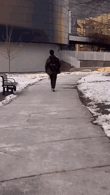 a person walking down a snowy sidewalk with a backpack