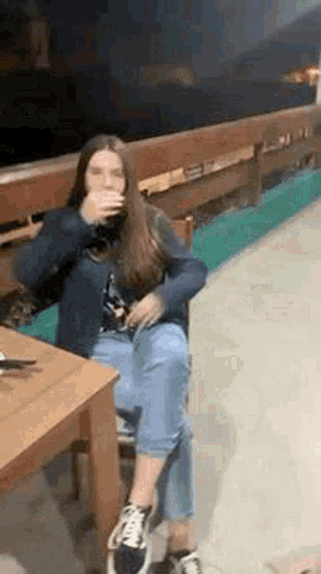 a woman is sitting at a table drinking a glass of wine .