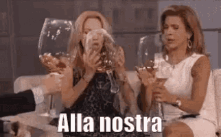 a group of women are sitting on a couch holding wine glasses and drinking wine .