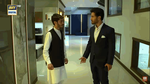 two men are standing in a hallway with ary digital on the bottom right
