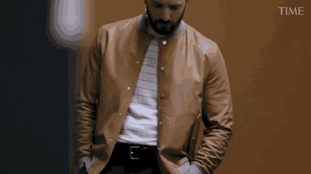 a man wearing a brown leather jacket is standing in front of a time advertisement
