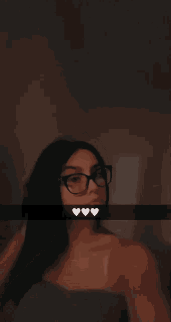 a woman wearing glasses takes a selfie with hearts on her face
