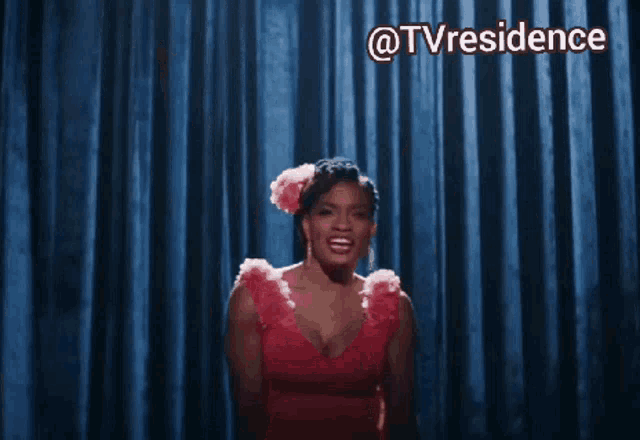 a woman in a red dress is dancing in front of a blue curtain with the words @tvresidence written above her
