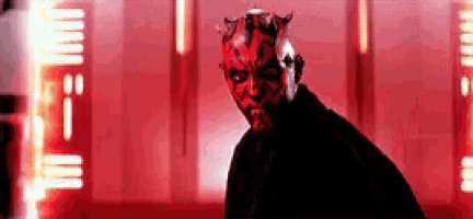 darth maul from star wars is wearing a red mask and standing in front of a red background .