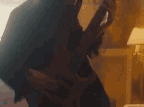 a woman is playing a guitar in a dark room while a man is holding her .