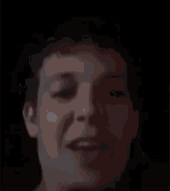 a close up of a person 's face with their mouth open in a dark room .