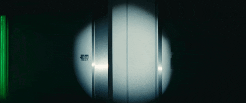 a dark room with a light shining on a door that says ' emergency exit '