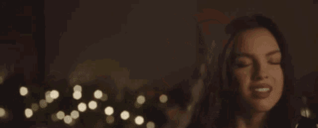 a woman is singing into a microphone with her eyes closed in front of a christmas tree .