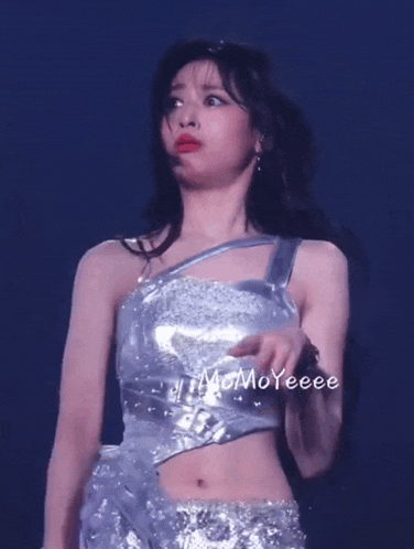 a woman in a silver top and skirt is standing on a stage with momoyeee written on the bottom