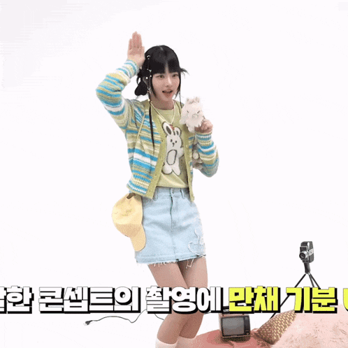 a girl in a striped sweater and denim skirt holds a teddy bear
