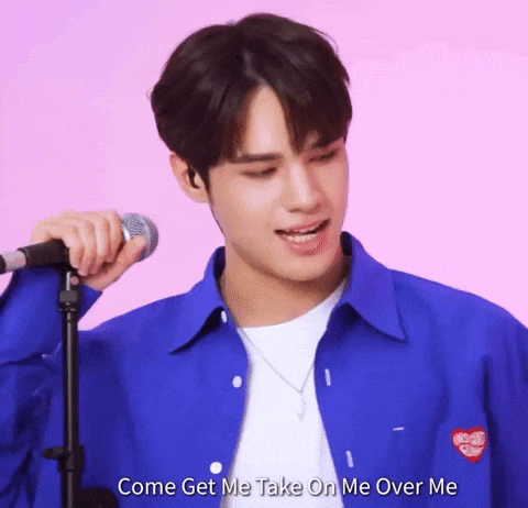 a young man is singing into a microphone while wearing a blue jacket .