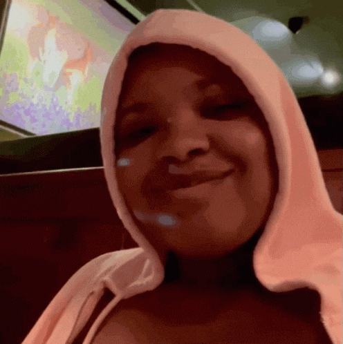 a woman wearing a pink hoodie is smiling