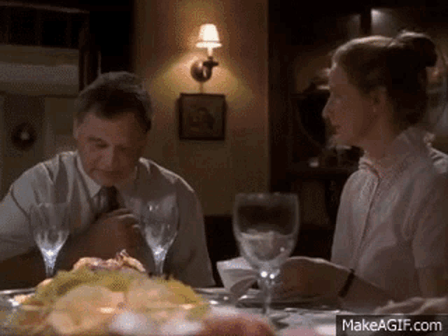 a man and a woman are sitting at a table with glasses of wine .