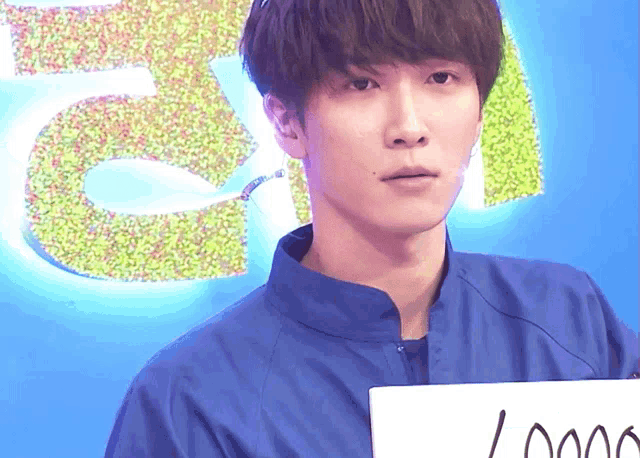 a young man in a blue jacket holds a sign that says ' i love you '
