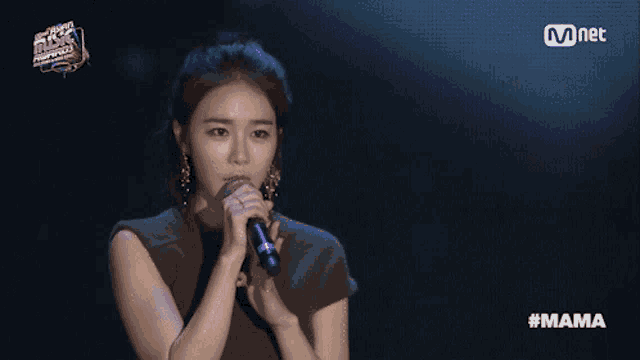 a woman singing into a microphone with the hashtag #mama on the screen