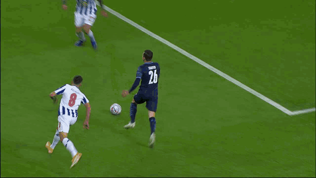 a soccer player with the number 26 on his back kicks the ball