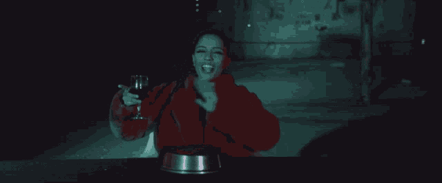 a woman in a red coat is holding a wine glass