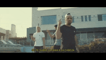 a group of men are standing in front of a building with the words se te subio la fame a la cabeza written below them