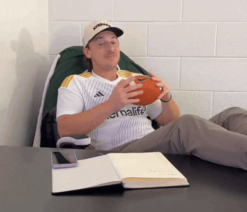 a man wearing a herbalife jersey holds a football