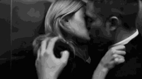 a man and woman are kissing in an elevator .