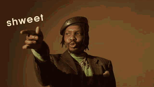 a man in a suit and beret is pointing at the word shweet