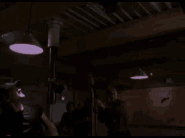 a man wearing a blue hat stands in a dark room