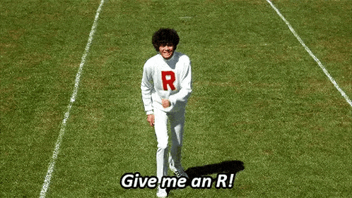 a man in a white sweatshirt with the letter r on it is jumping in the air on a field .