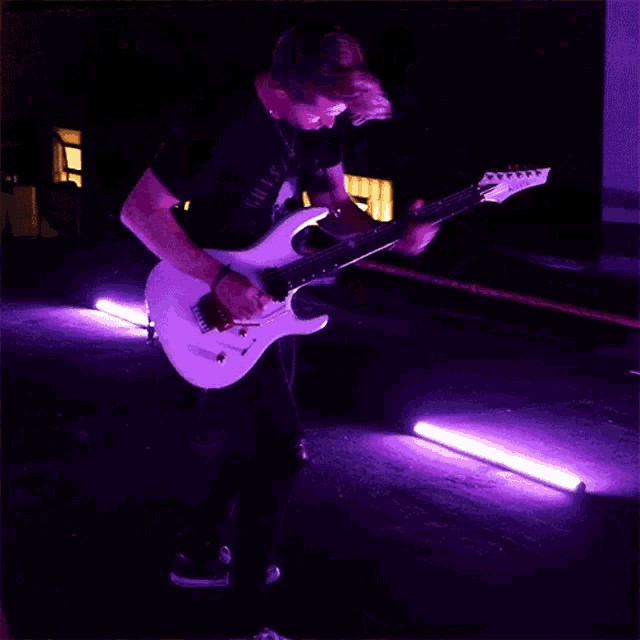 a man playing a guitar with a rolling stones logo in the background