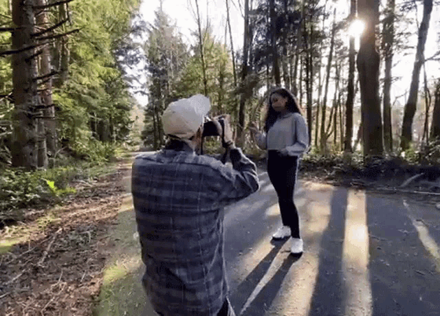 a man taking a picture of a woman in the woods