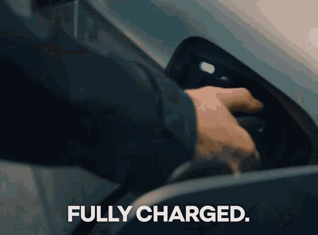 a person is charging an electric car and the word fully charged is on the screen