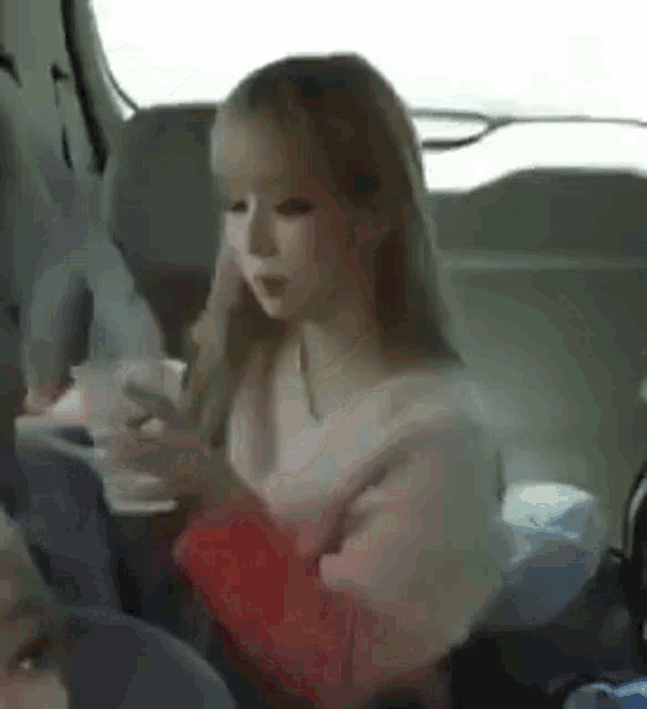 a woman is sitting in the back seat of a car drinking a cup of coffee .