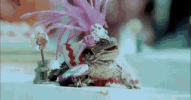 a bearded dragon wearing a pink hat and a pink feathered headpiece is sitting on a table .