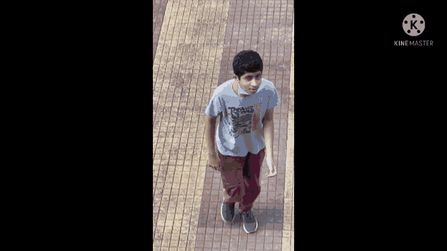 a young boy wearing a t-shirt that says texas is walking down a tiled walkway