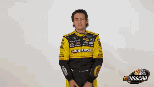 a man in a yellow and black nascar uniform waves