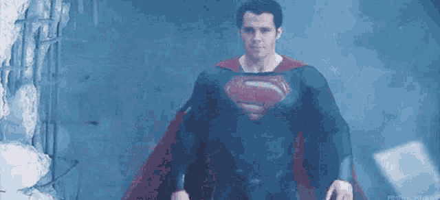 a man in a superman costume is standing in a dark room .