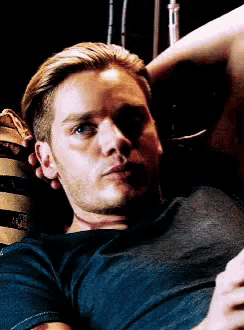 a man in a blue shirt is laying down with his hand on his head